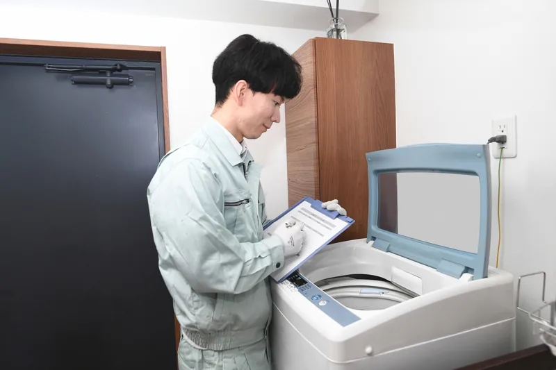 洗濯機の設置状況を確認し記録するスタッフ